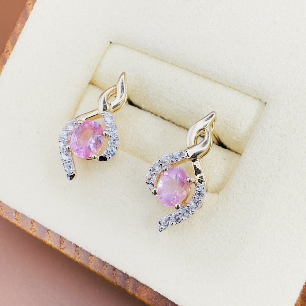 A pair of 10ct yellow gold stud earrings featuring oval pink sapphires encased in swirling diamond-accented mounts.