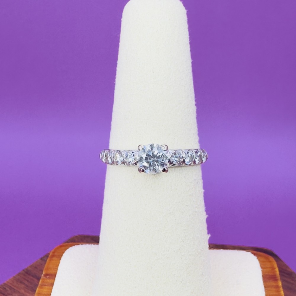 An 18ct white gold engagement ring featuring a round brilliant-cut central diamond flanked by smaller diamonds set along the shoulders.