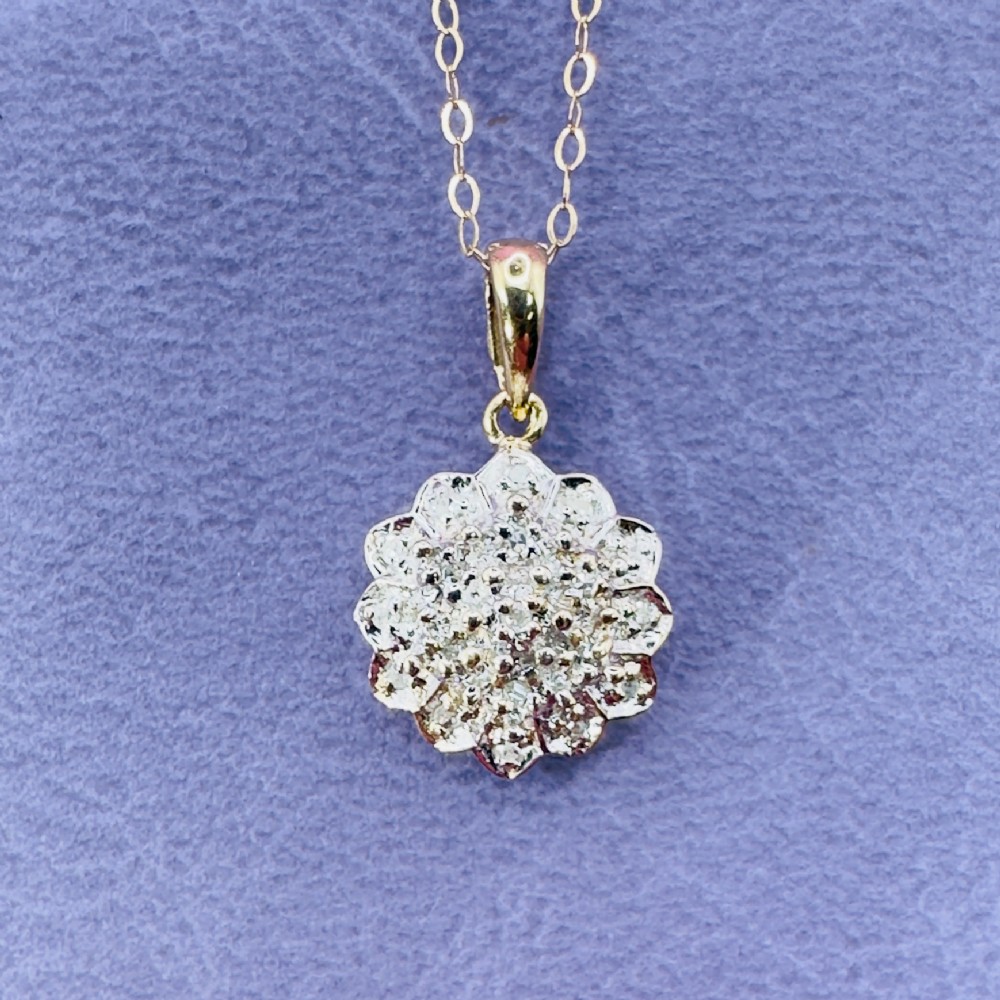 A 9ct yellow gold starburst cluster pendant with pave-set diamonds suspended from a fine gold link chain.
