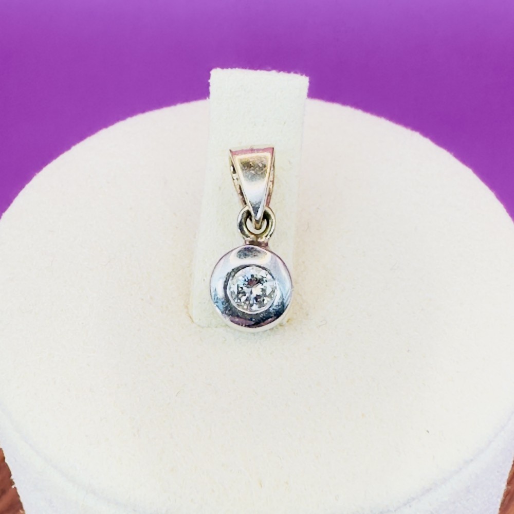 An 18ct white gold pendant featuring a bezel-set round diamond suspended from a tapered bail.
