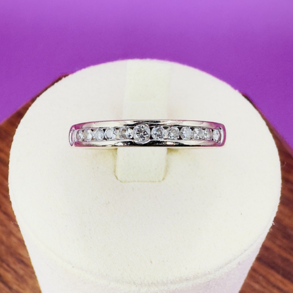 An 18ct white gold half eternity ring set with a row of round brilliant cut diamonds along the top of the polished band.