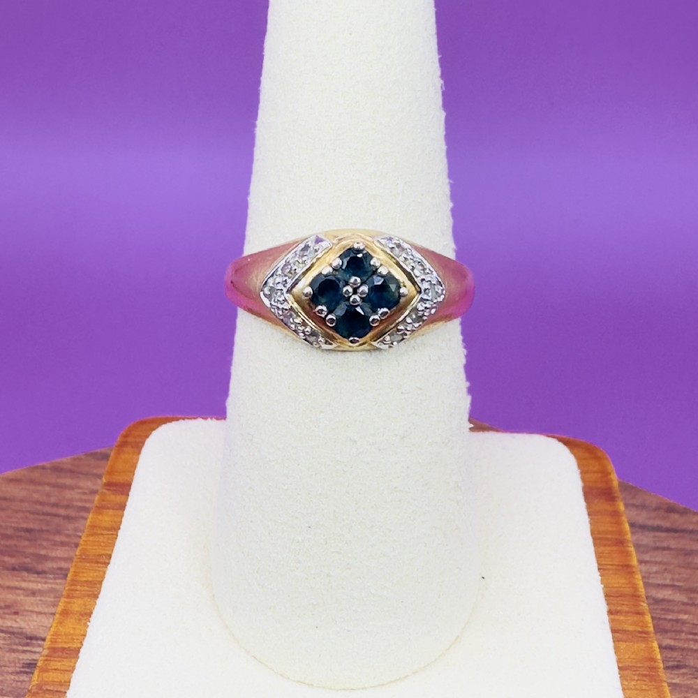 An 18ct yellow gold ring featuring a central diamond-shaped panel set with four round blue sapphires, flanked by diamond-set shoulders.