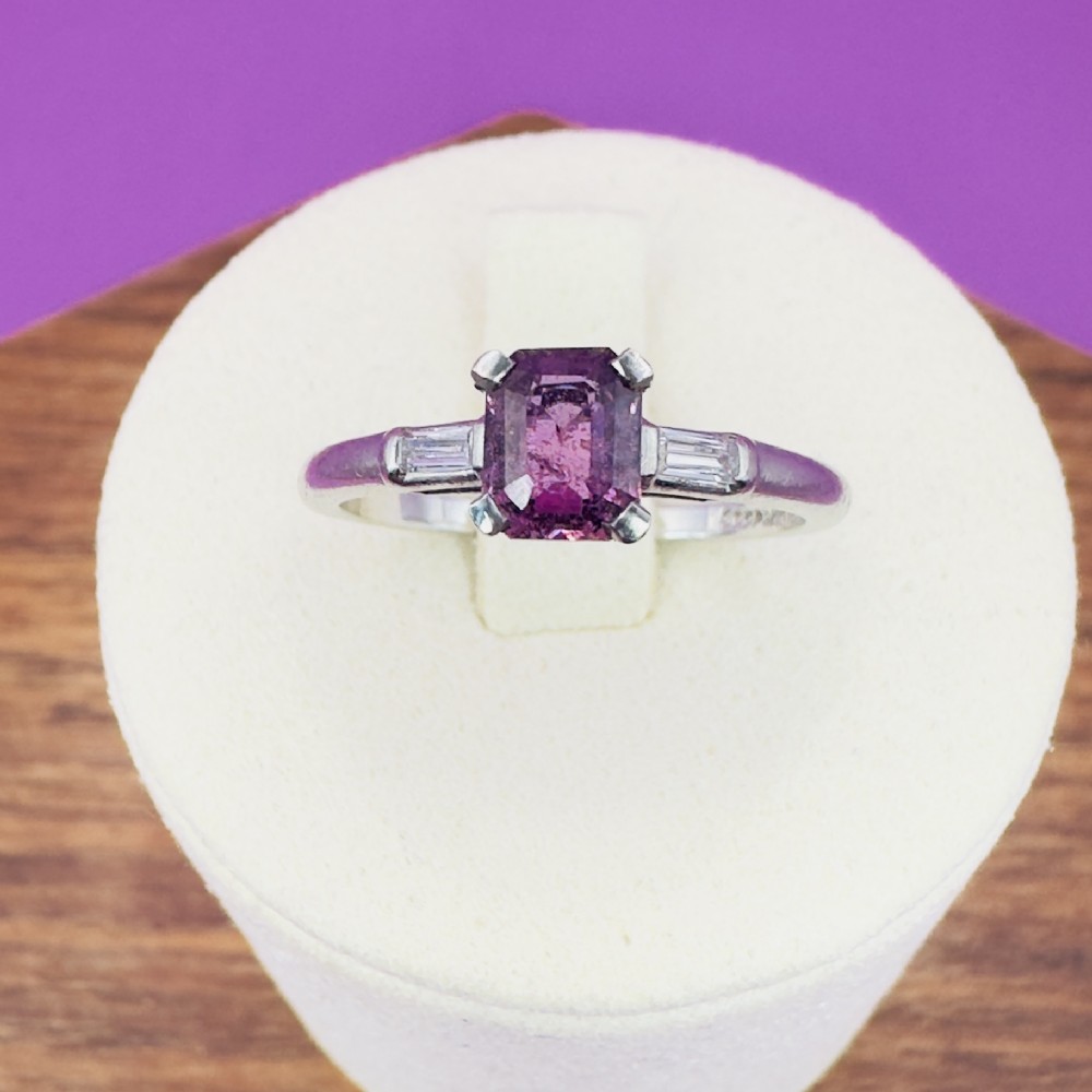 An Art Deco platinum ring set with a central rectangular pink sapphire flanked by two baguette-cut diamonds.