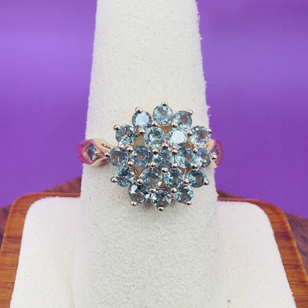 A 14ct yellow gold cluster ring set with round light green tsavorite garnets in a multi-tier floral arrangement.