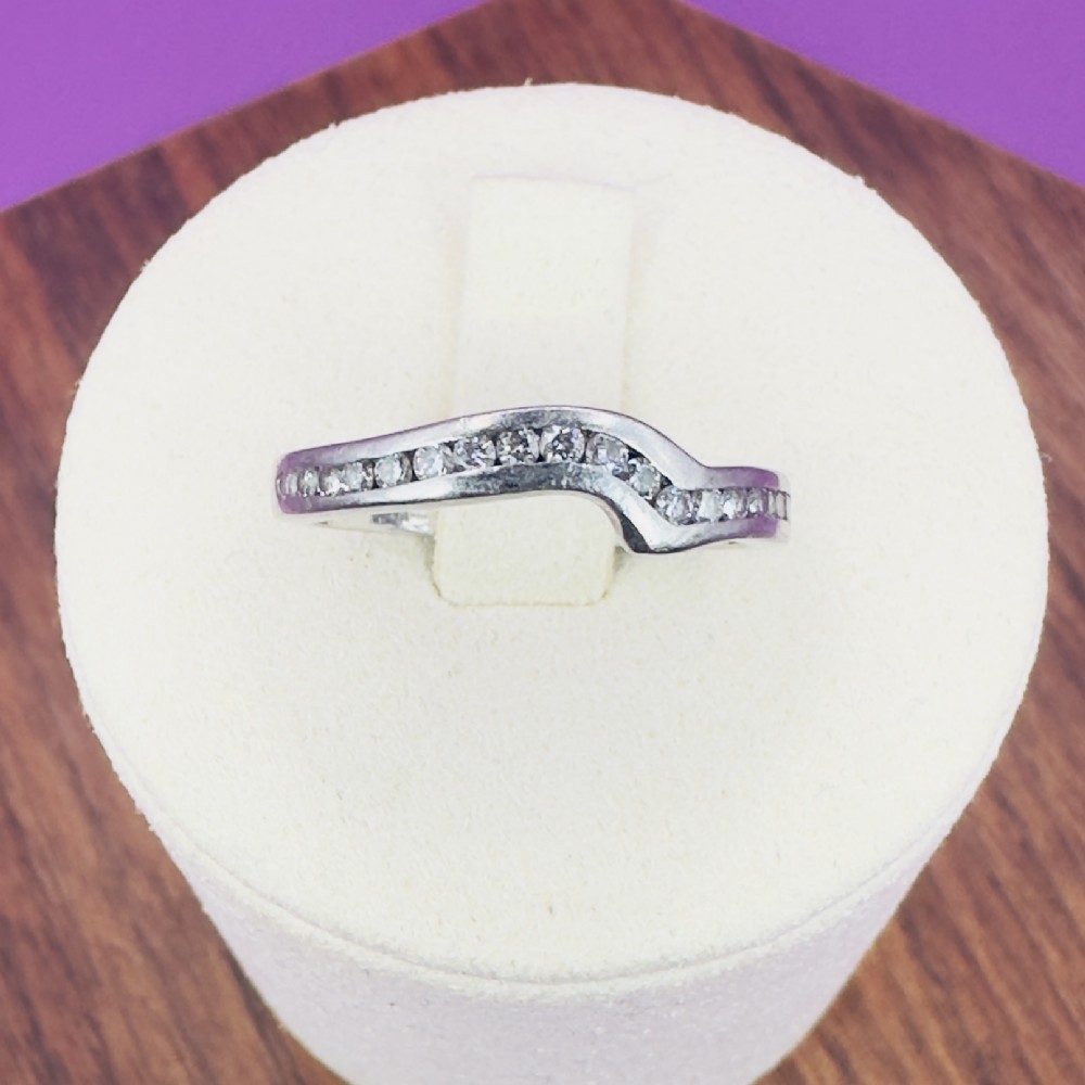 A platinum off-centre wishbone band channel-set with round brilliant-cut diamonds across the upper half.