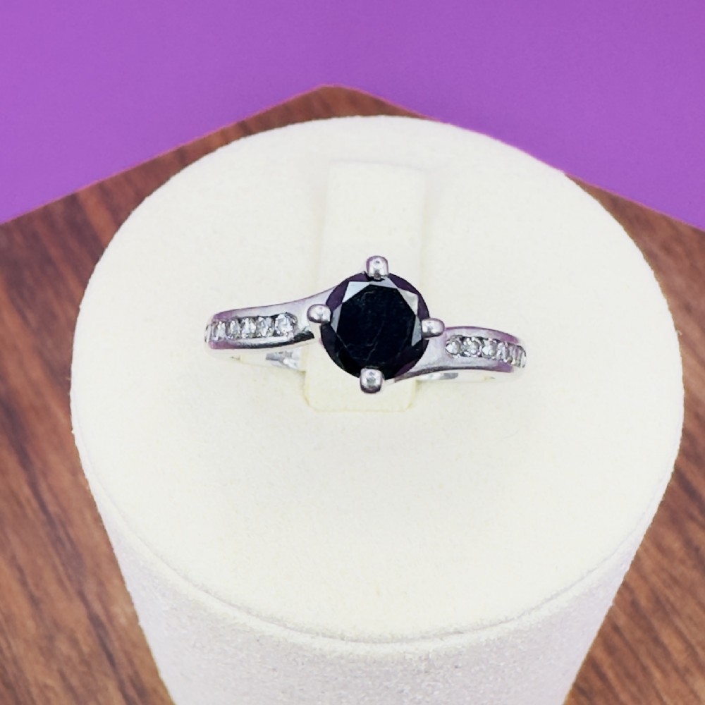 A platinum twist solitaire ring featuring a round brilliant black diamond held in a four-claw setting with small white diamonds accenting the shoulders.