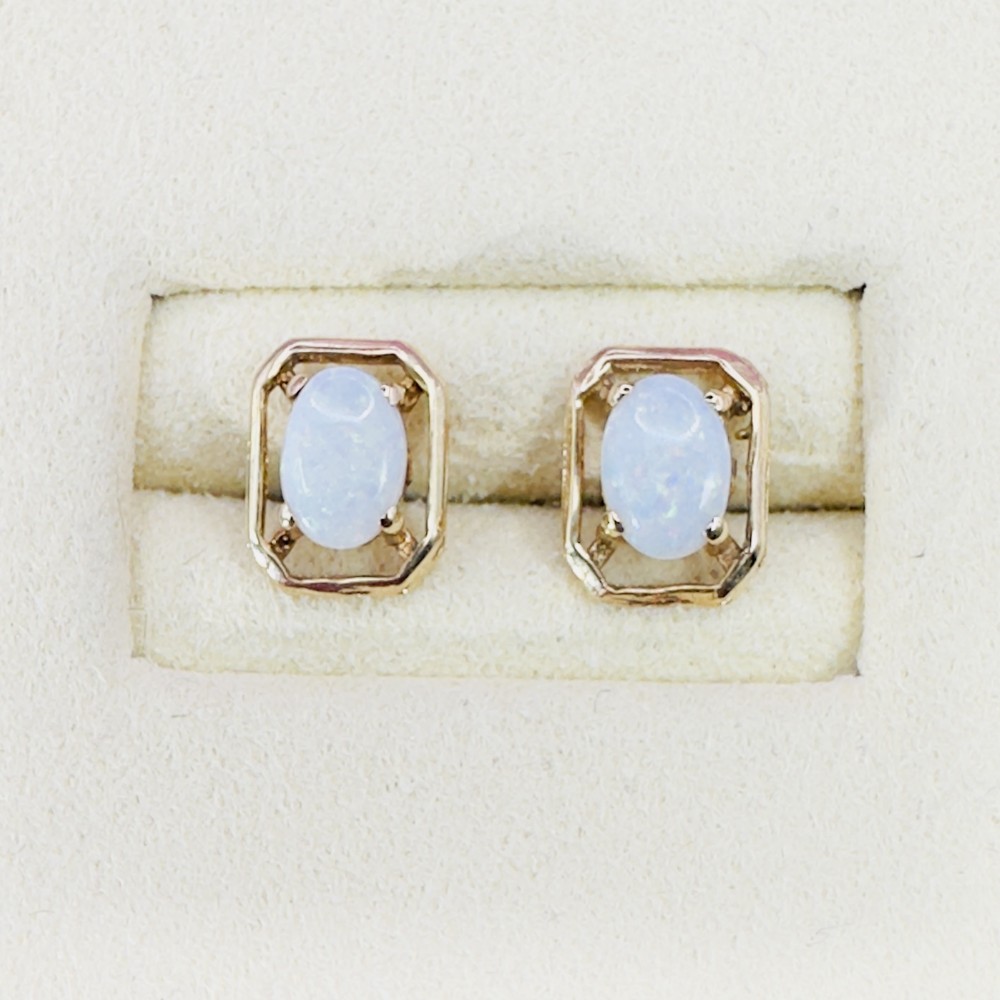 A pair of 9ct yellow gold stud earrings featuring central oval cabochon opals set inside geometric openwork frames.