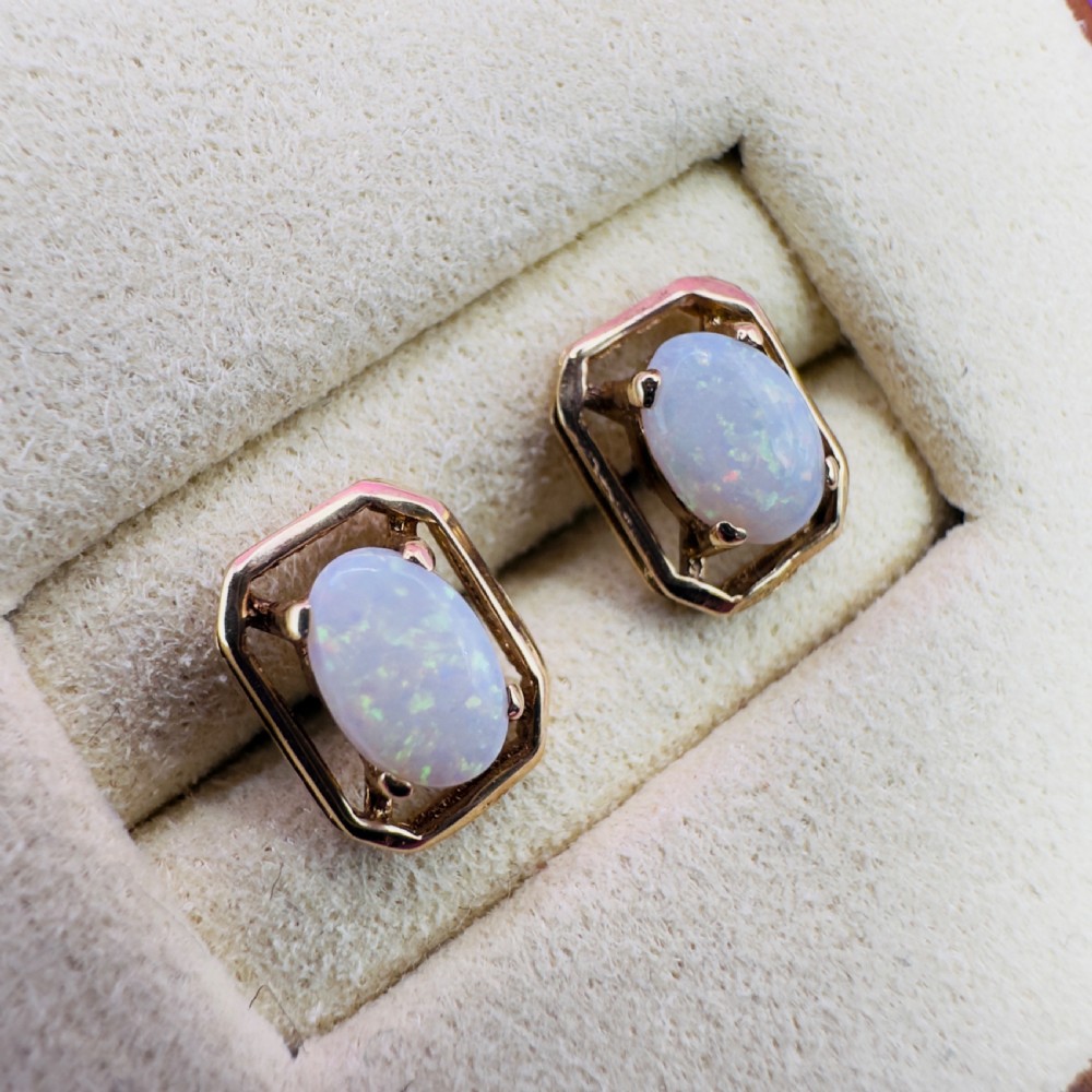 A pair of 9ct yellow gold stud earrings featuring central oval cabochon opals set inside geometric openwork frames. View VI