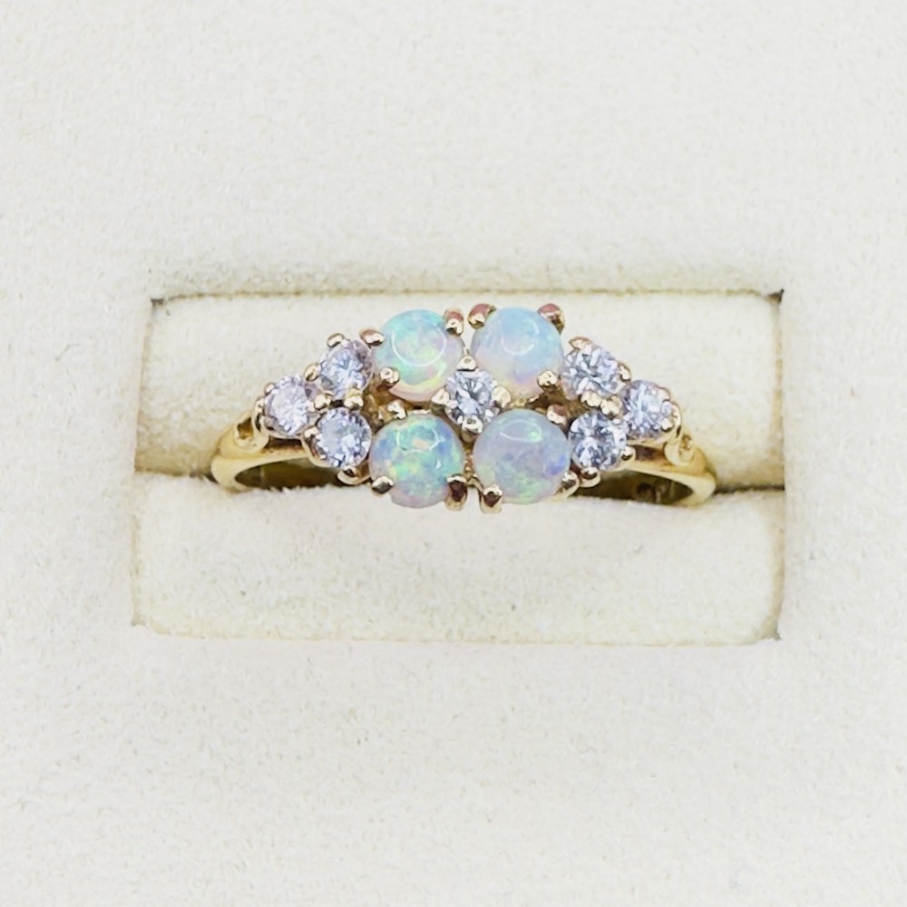 An 18ct yellow gold ring set with four round cabochon opals flanked by small round diamonds in a cluster design.