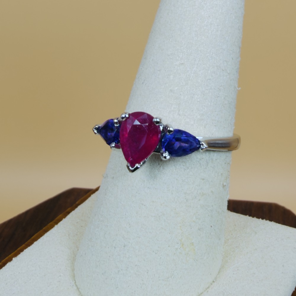A platinum three-stone ring featuring a central pear-cut red ruby flanked by two pear-cut purple amethysts. View VII