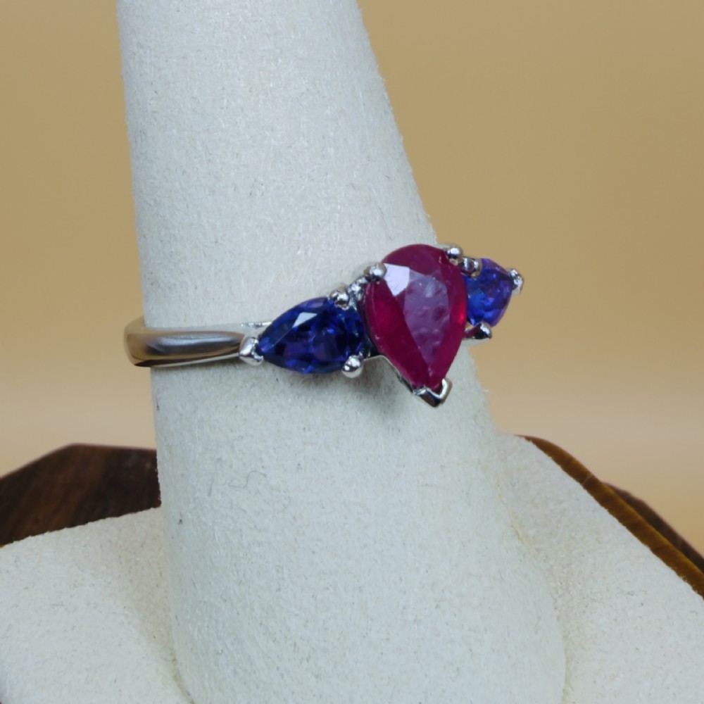 A platinum three-stone ring featuring a central pear-cut red ruby flanked by two pear-cut purple amethysts. View VIII