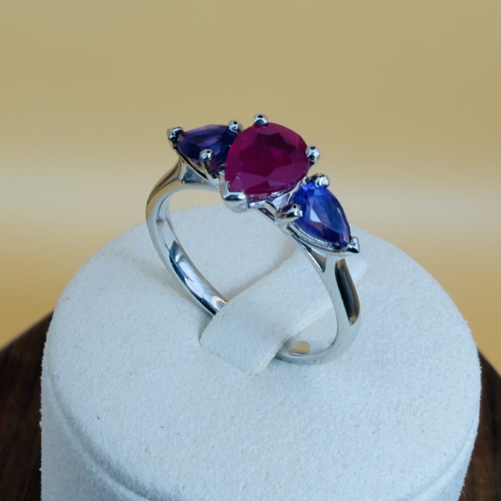 A platinum three-stone ring featuring a central pear-cut red ruby flanked by two pear-cut purple amethysts. View IX