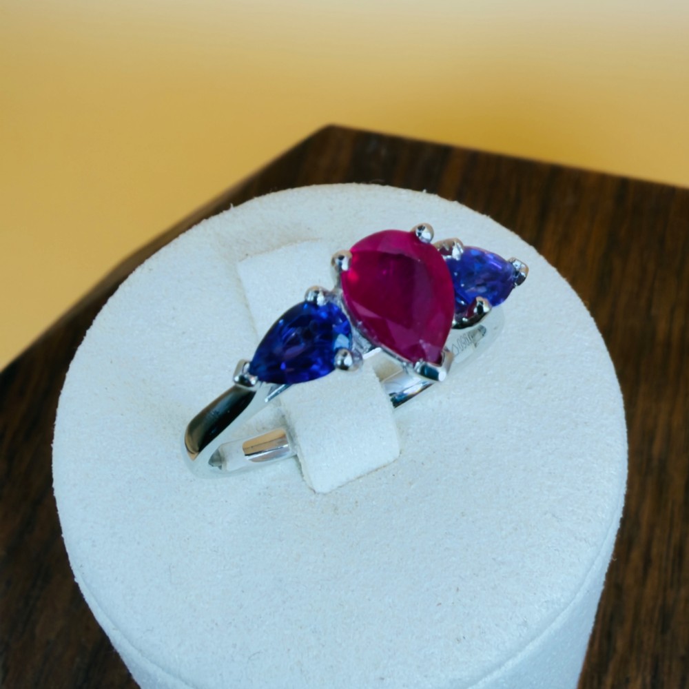 A platinum three-stone ring featuring a central pear-cut red ruby flanked by two pear-cut purple amethysts. View XI