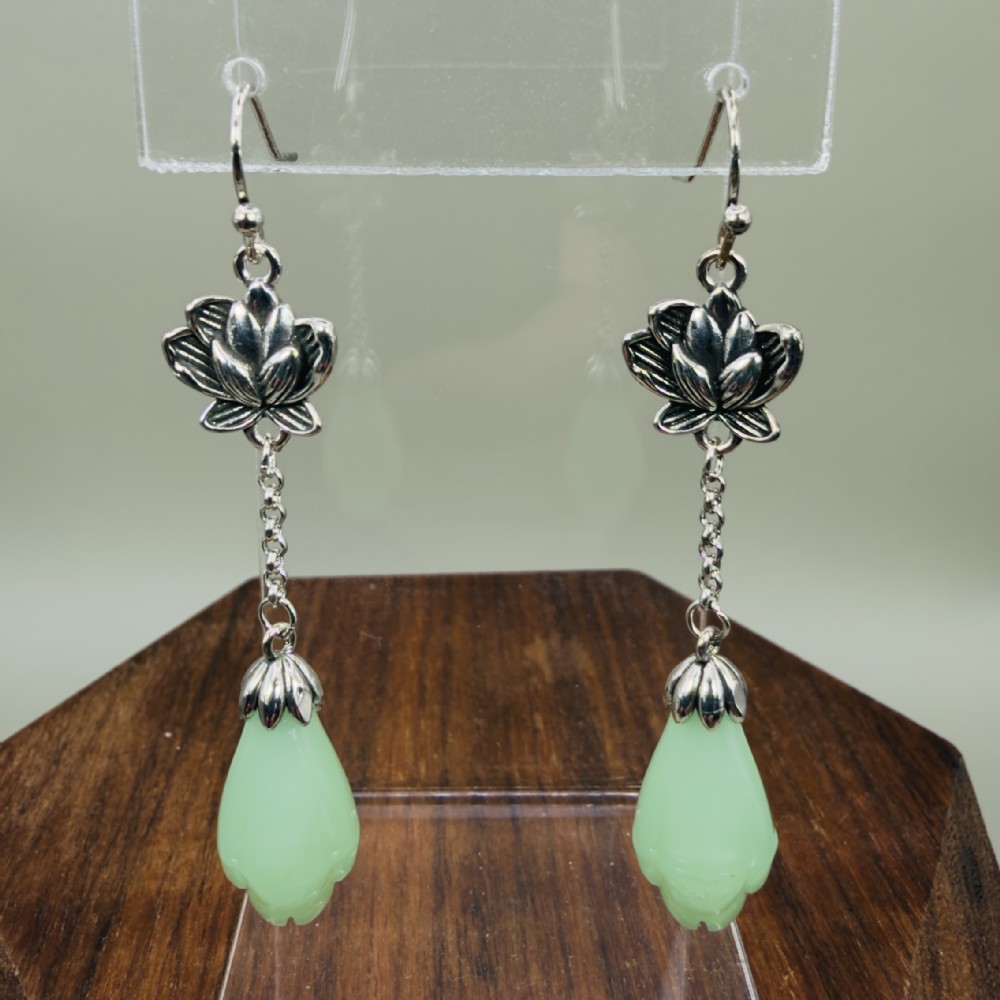 Pair of sterling silver drop earrings with lotus flower motif mounts, delicate trace chains, and carved mint-green chalcedony teardrop pendants on hook wires.