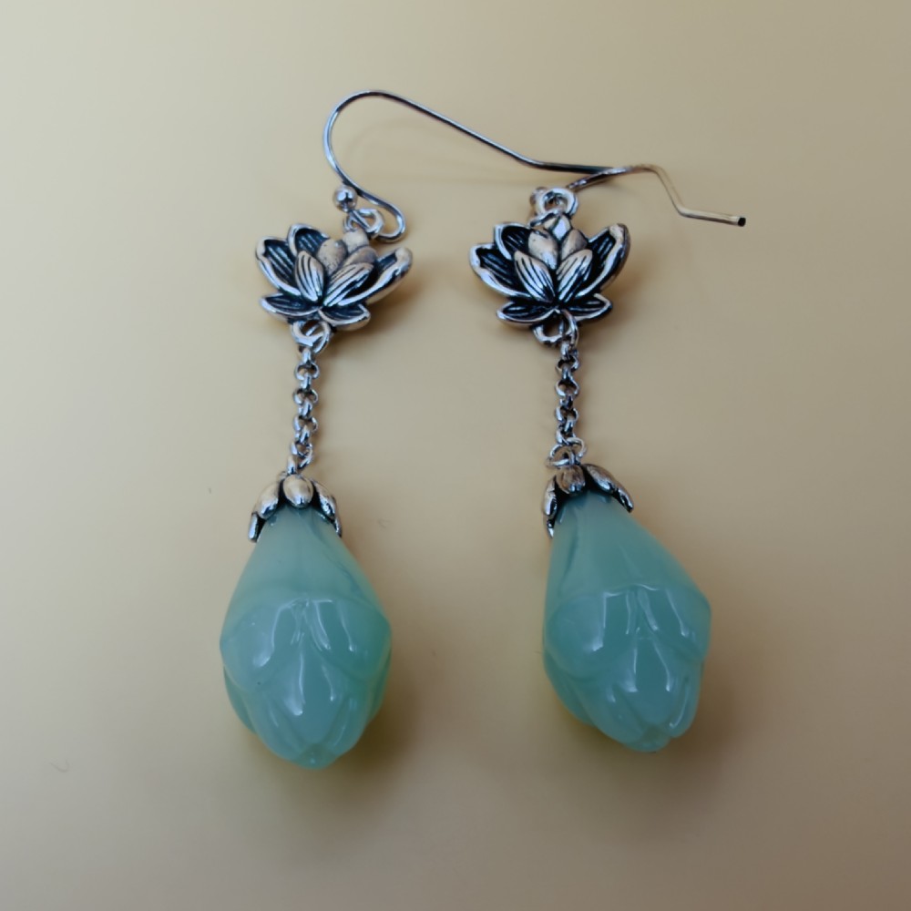 Pair of sterling silver drop earrings with lotus flower motif mounts, delicate trace chains, and carved mint-green chalcedony teardrop pendants on hook wires. View V