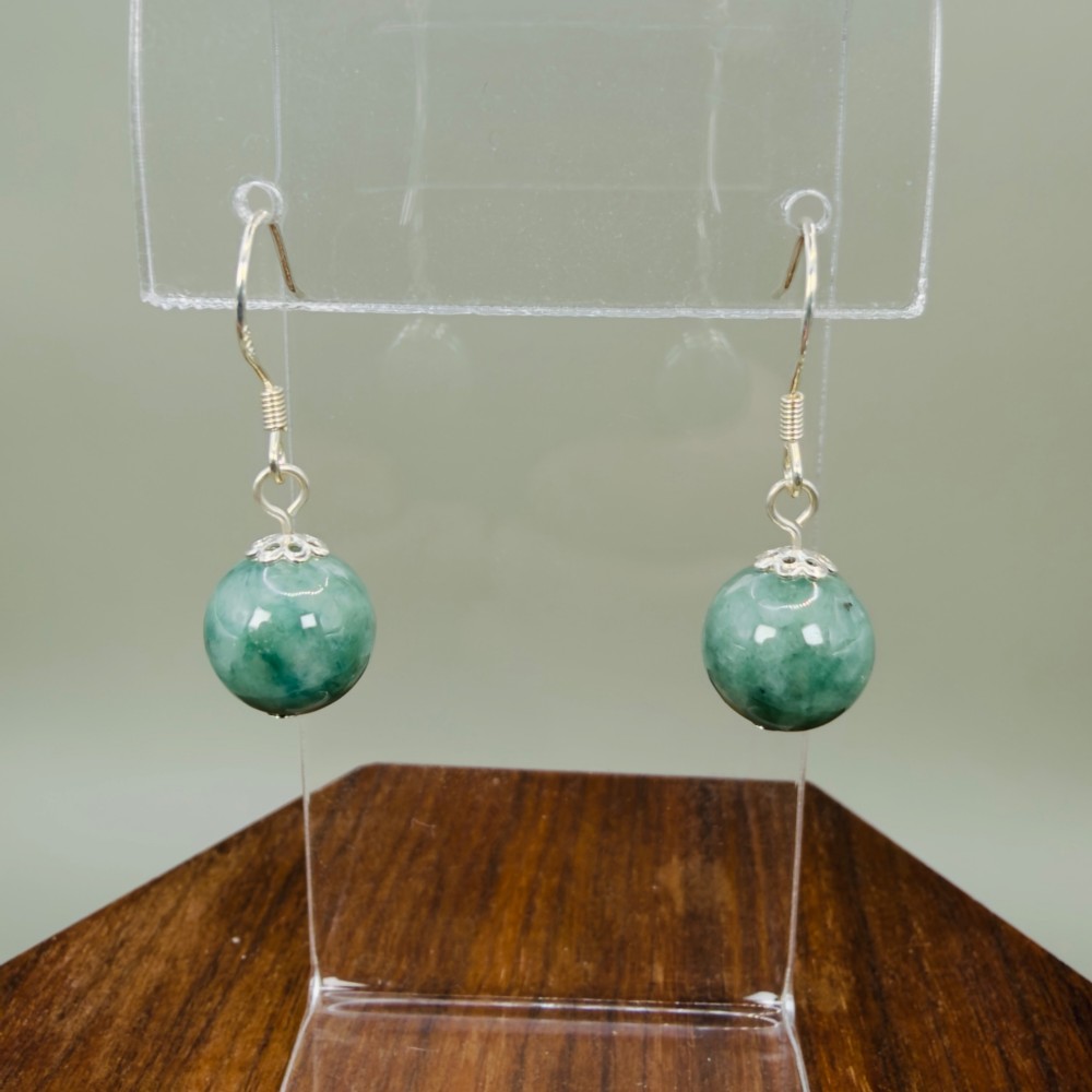 A pair of spherical green jade bead dangle earrings with ornate sterling silver caps and wire hook fittings.