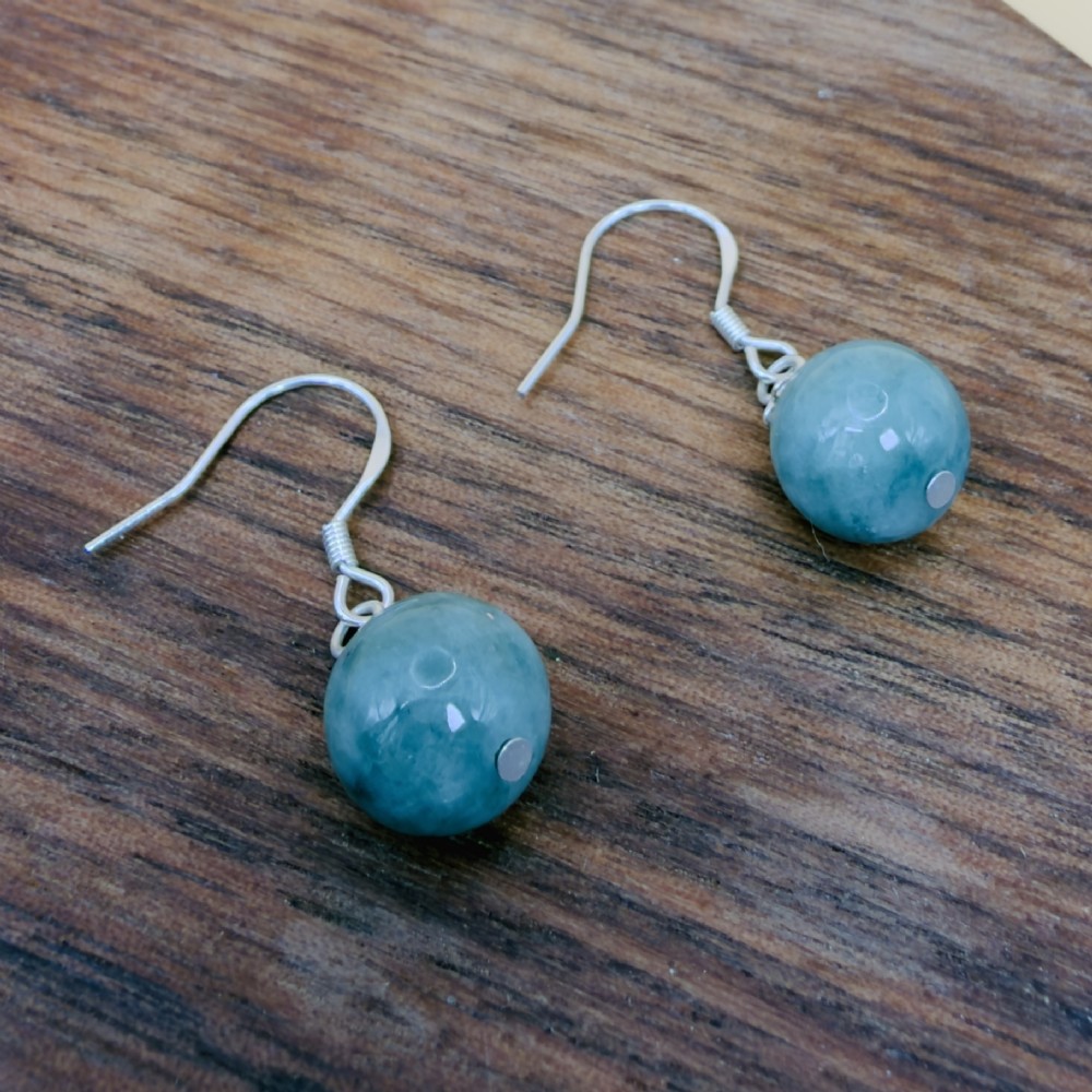 A pair of spherical green jade bead dangle earrings with ornate sterling silver caps and wire hook fittings. View V