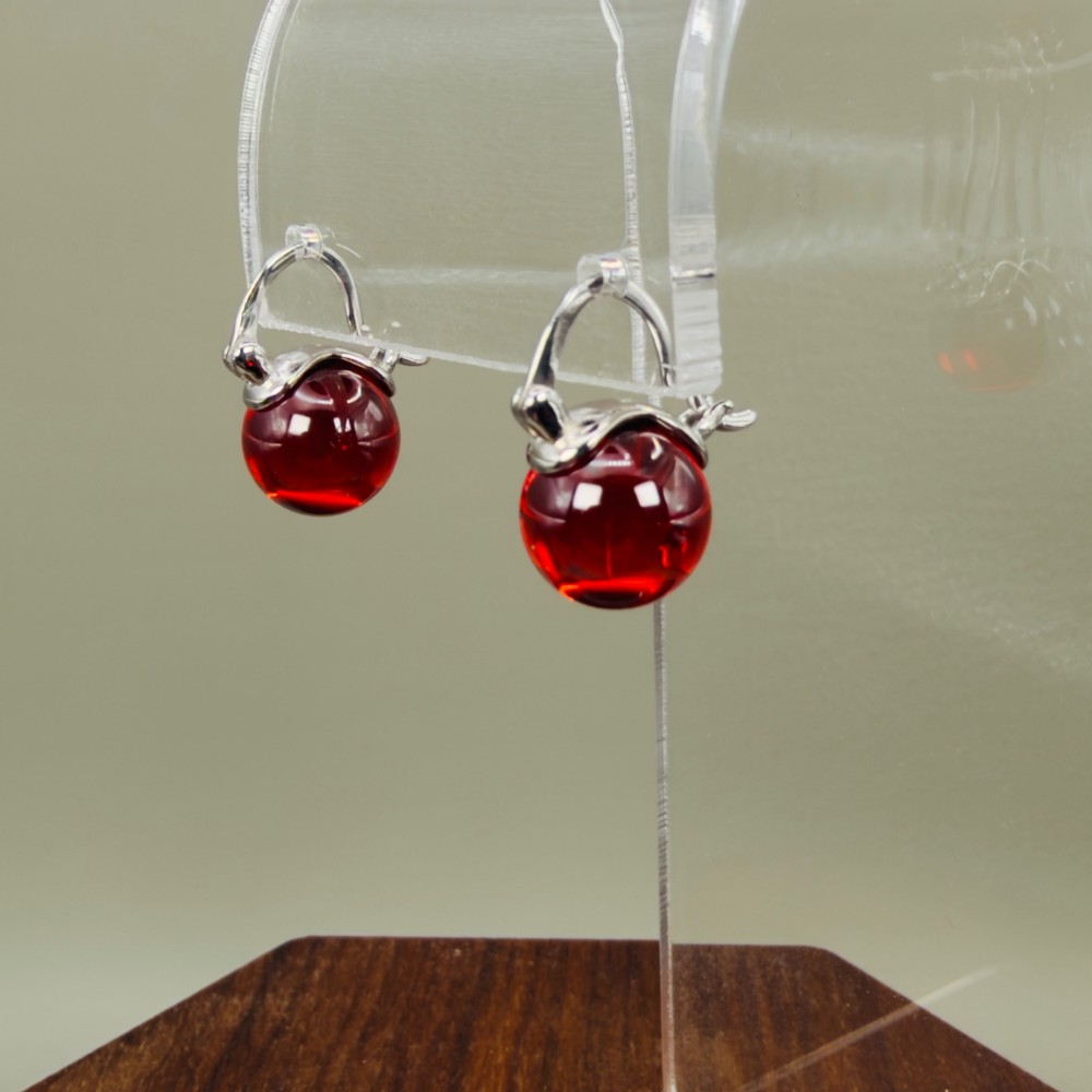 A pair of sterling silver drop earrings featuring translucent spherical red synthetic ruby beads suspended from hinge back hooks. View II