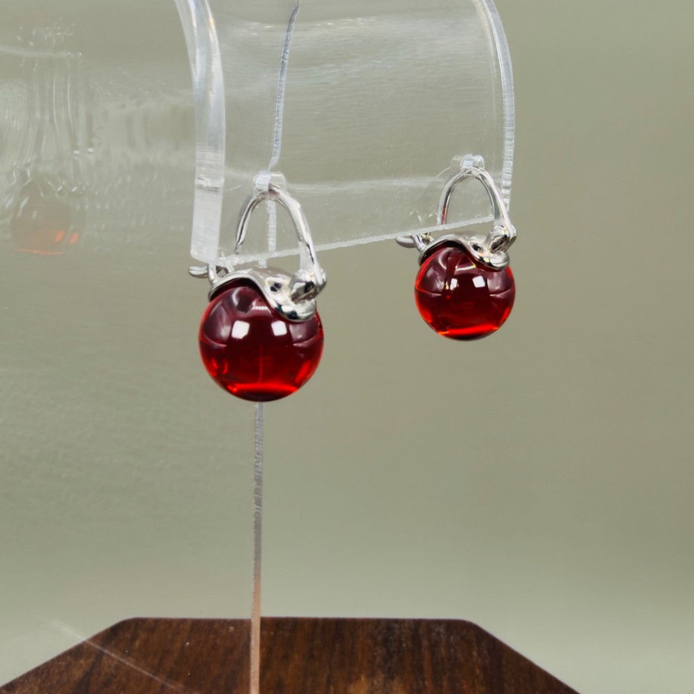 A pair of sterling silver drop earrings featuring translucent spherical red synthetic ruby beads suspended from hinge back hooks. View III