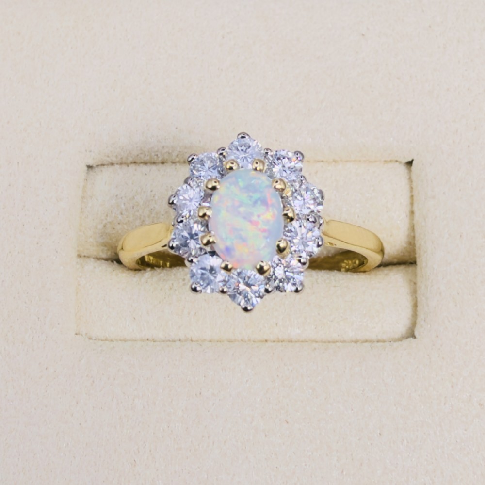 An 18ct yellow gold ring featuring an oval cabochon opal surrounded by a halo of brilliant-cut diamonds. View II