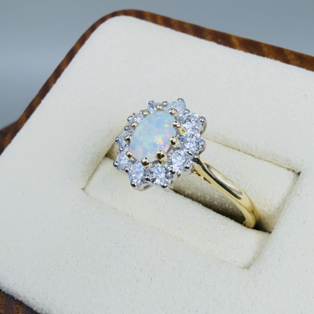 An 18ct yellow gold ring featuring an oval cabochon opal surrounded by a halo of brilliant-cut diamonds. View III
