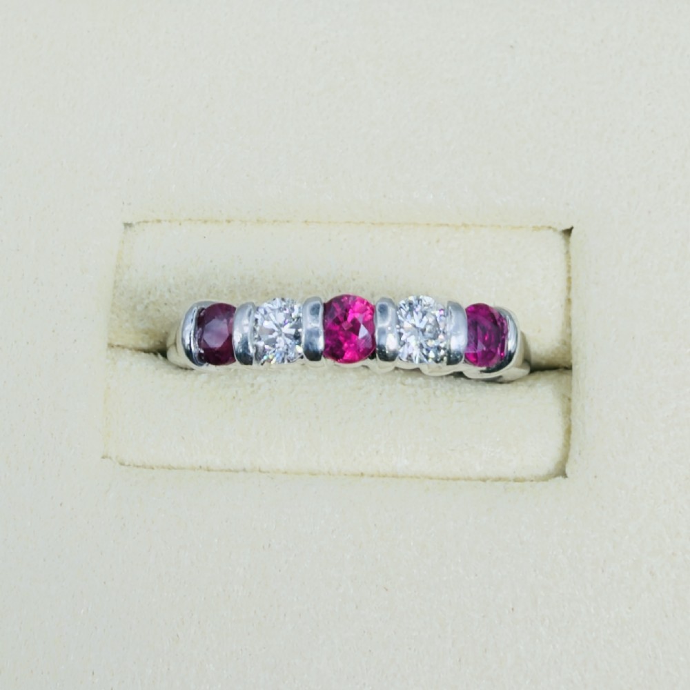 An 18ct white gold band ring featuring three round red rubies alternating with two round diamonds in a bar setting. View II