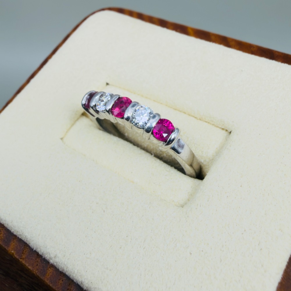 An 18ct white gold band ring featuring three round red rubies alternating with two round diamonds in a bar setting. View III