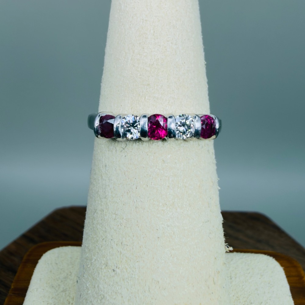 An 18ct white gold band ring featuring three round red rubies alternating with two round diamonds in a bar setting. View V