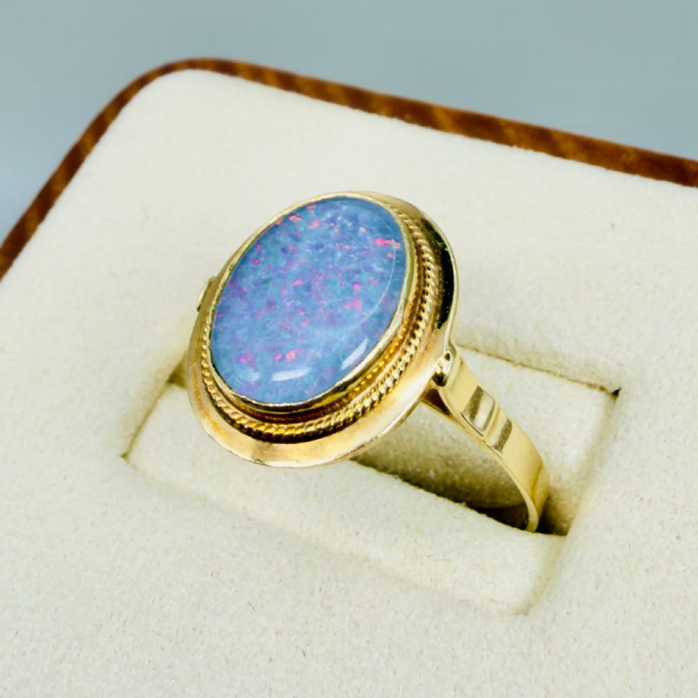 An oval blue boulder opal cabochon gemstone set in a 14ct yellow gold ring with a rope twist bezel border. View III