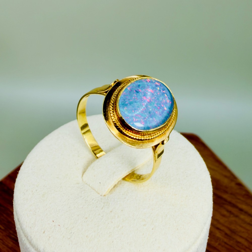 An oval blue boulder opal cabochon gemstone set in a 14ct yellow gold ring with a rope twist bezel border. View IX
