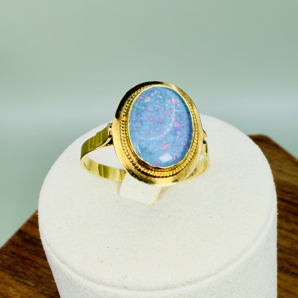 An oval blue boulder opal cabochon gemstone set in a 14ct yellow gold ring with a rope twist bezel border. View XI