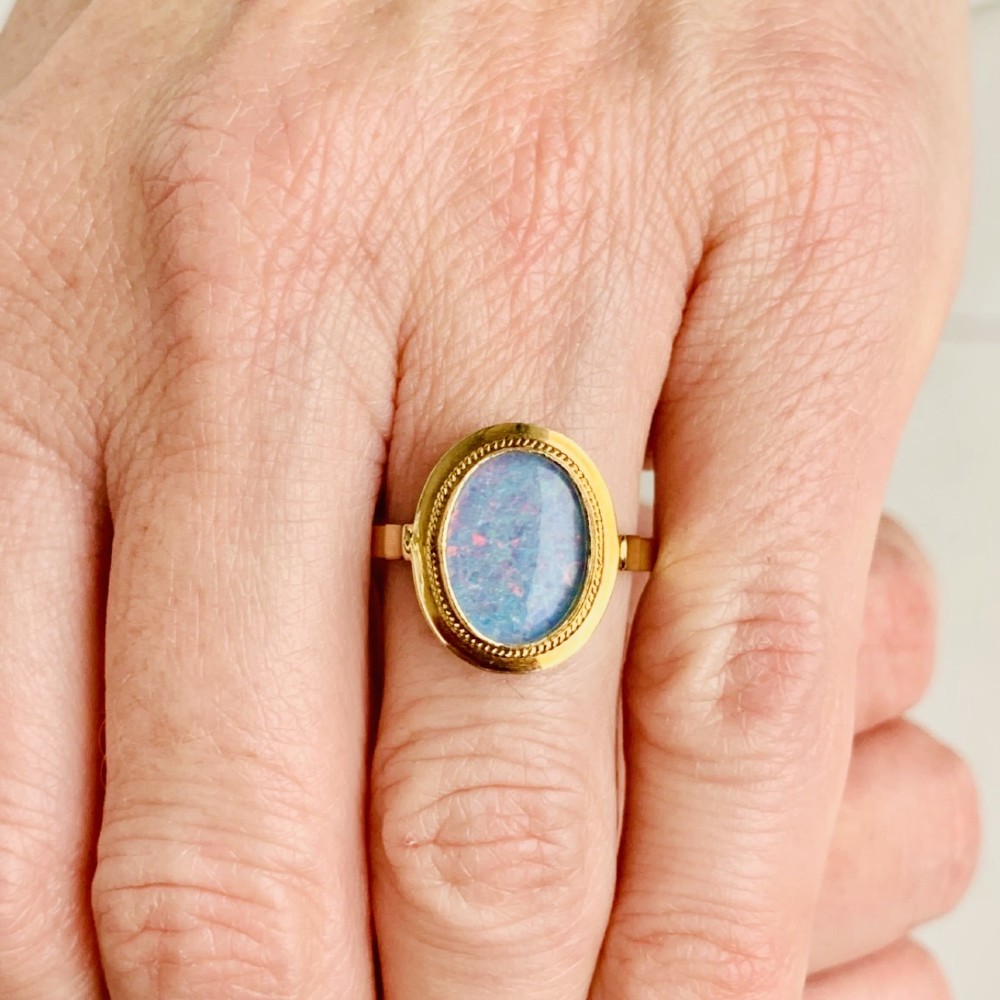 An oval blue boulder opal cabochon gemstone set in a 14ct yellow gold ring with a rope twist bezel border. View XII
