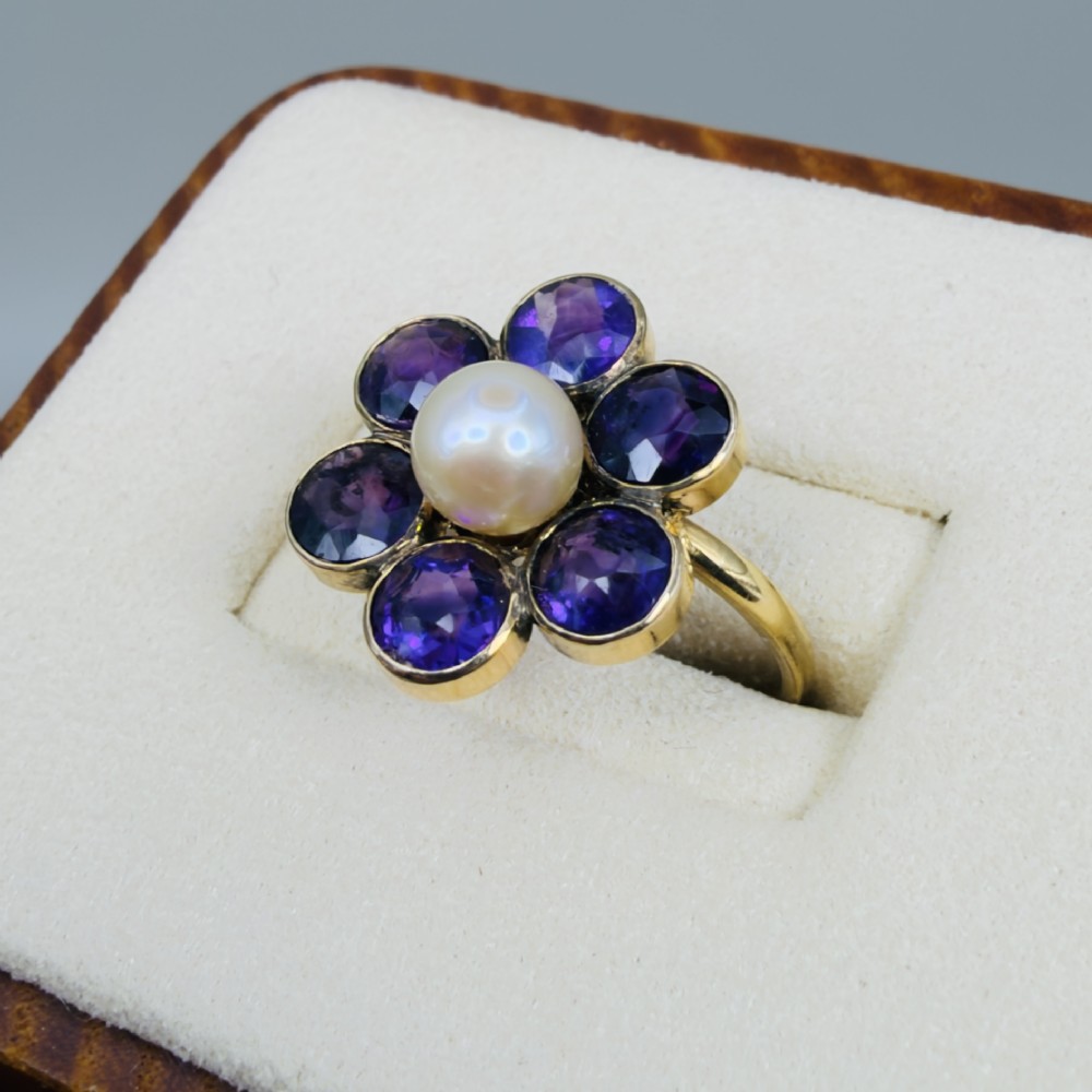 An 18ct gold Georgian cluster ring featuring a central round pearl encircled by six faceted purple amethysts in a floral arrangement. View III