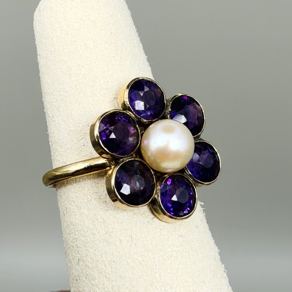 An 18ct gold Georgian cluster ring featuring a central round pearl encircled by six faceted purple amethysts in a floral arrangement. View VIII