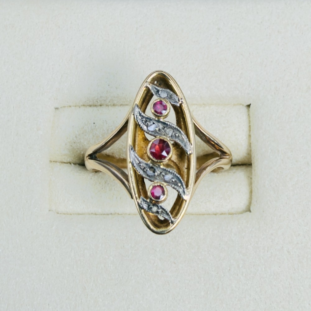 An 18ct gold Art Nouveau navette ring featuring three round rubies set within an openwork marquise-shaped mount detailed with diamonds. View II
