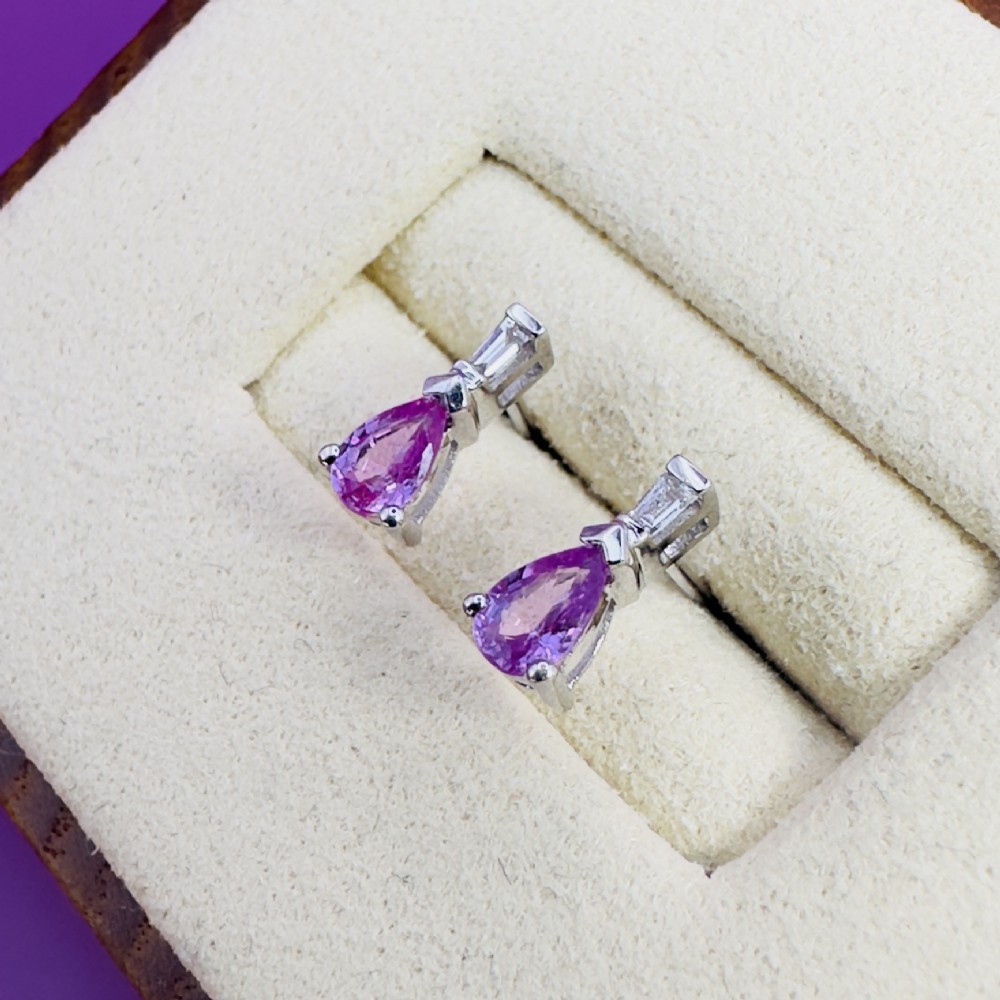 A pair of 18ct white gold stud earrings featuring pear-cut pink sapphires suspended beneath trapezoid-cut diamonds. View III