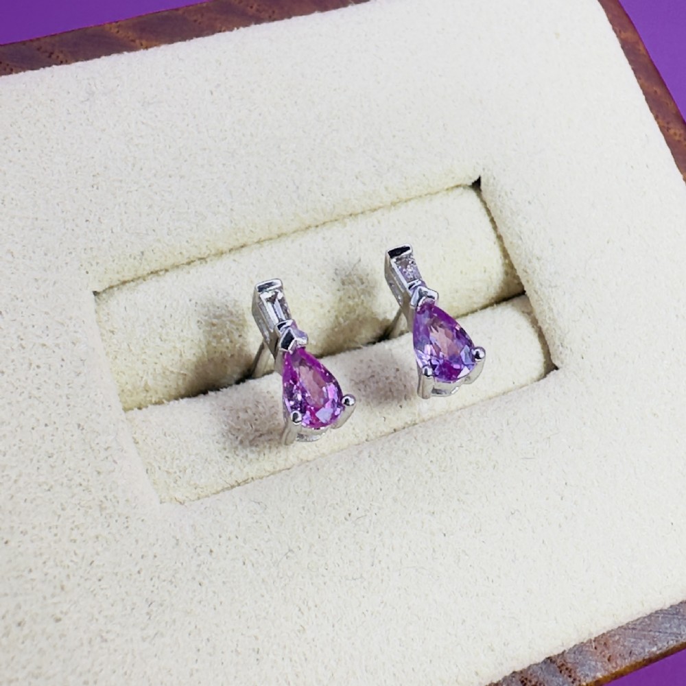 A pair of 18ct white gold stud earrings featuring pear-cut pink sapphires suspended beneath trapezoid-cut diamonds. View IV