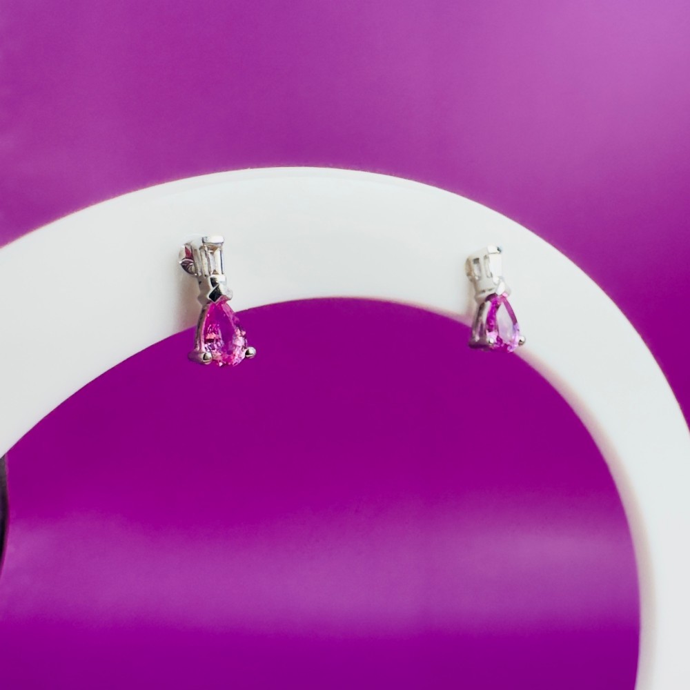 A pair of 18ct white gold stud earrings featuring pear-cut pink sapphires suspended beneath trapezoid-cut diamonds. View IX