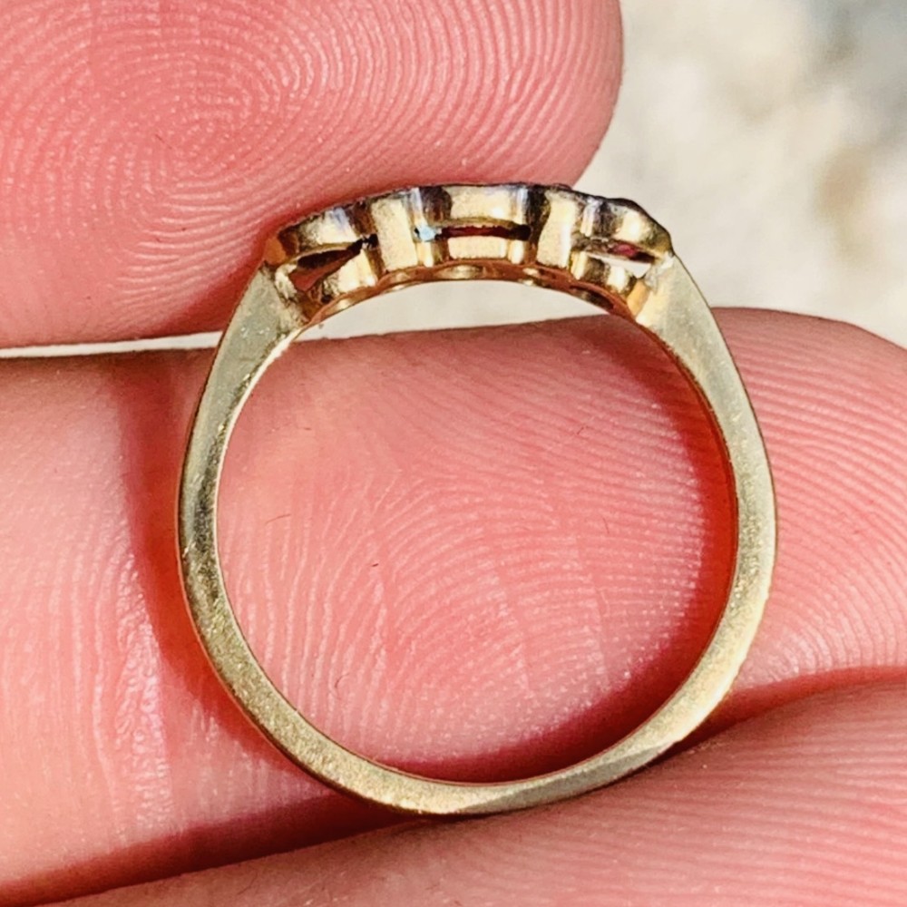 An 18ct yellow gold ring featuring three oval pinkish-red rubies interspersed with pairs of small round old-cut diamonds in a platinum setting. View VI
