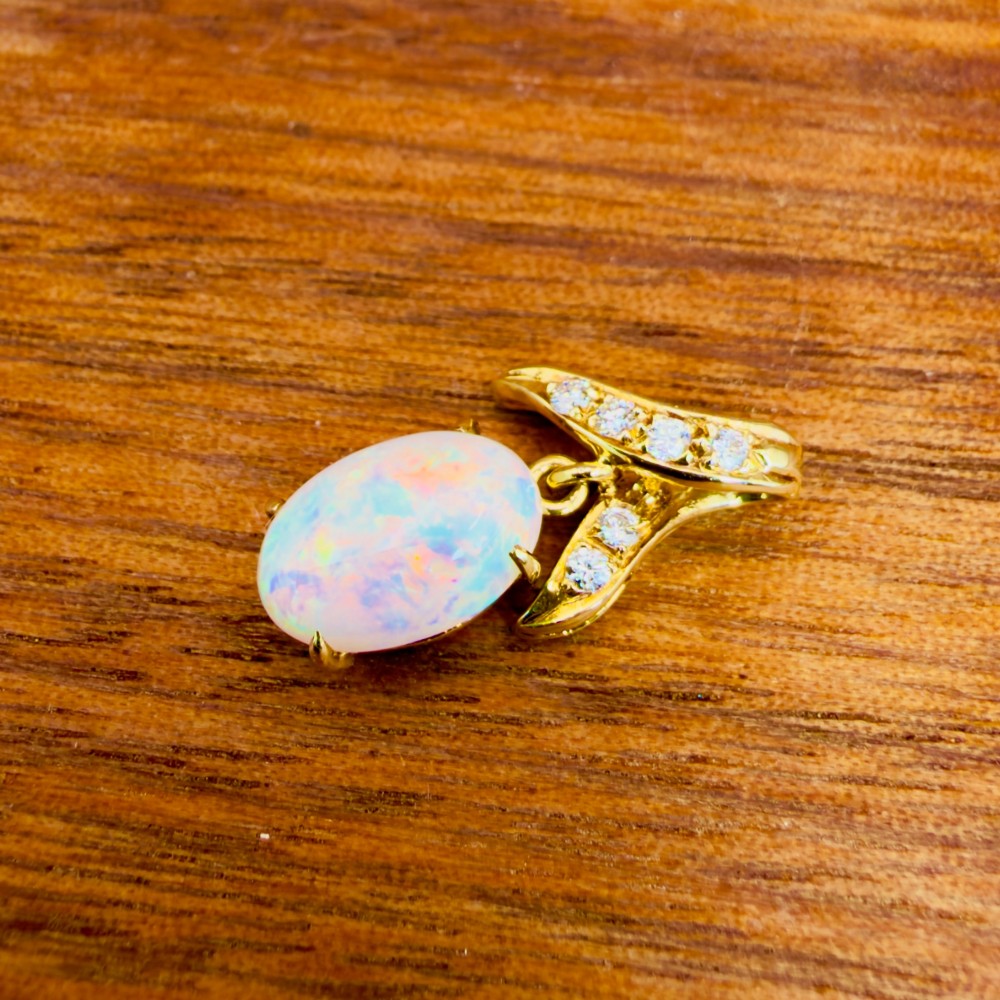 A 14ct yellow gold pendant featuring a claw-set cabochon opal hanging beneath a diamond-accented bail. View III