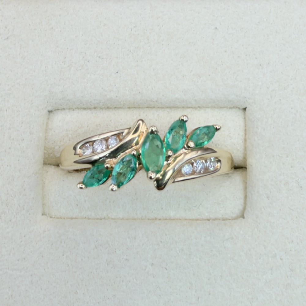 A 14ct yellow gold cluster ring set with five marquise-cut green emeralds flanked by channel-set diamonds. View II