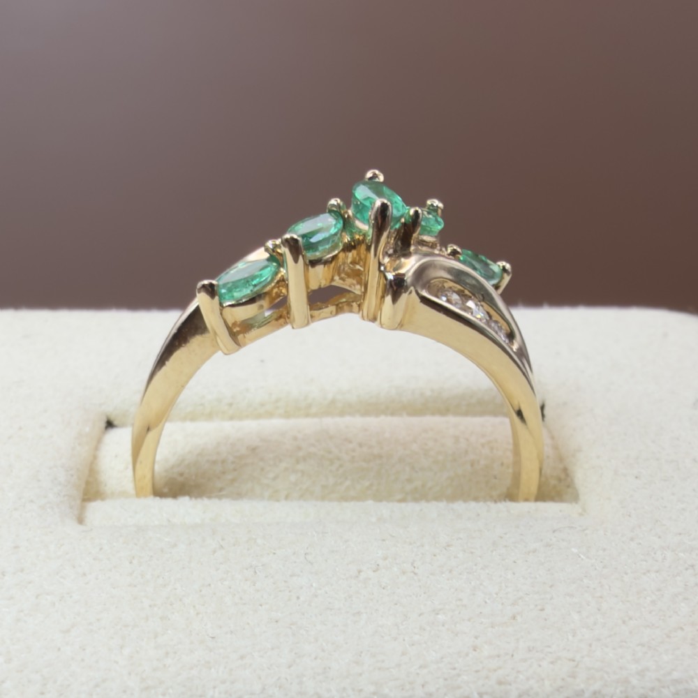 A 14ct yellow gold cluster ring set with five marquise-cut green emeralds flanked by channel-set diamonds. View V