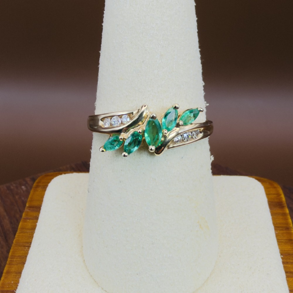 A 14ct yellow gold cluster ring set with five marquise-cut green emeralds flanked by channel-set diamonds. View VIII