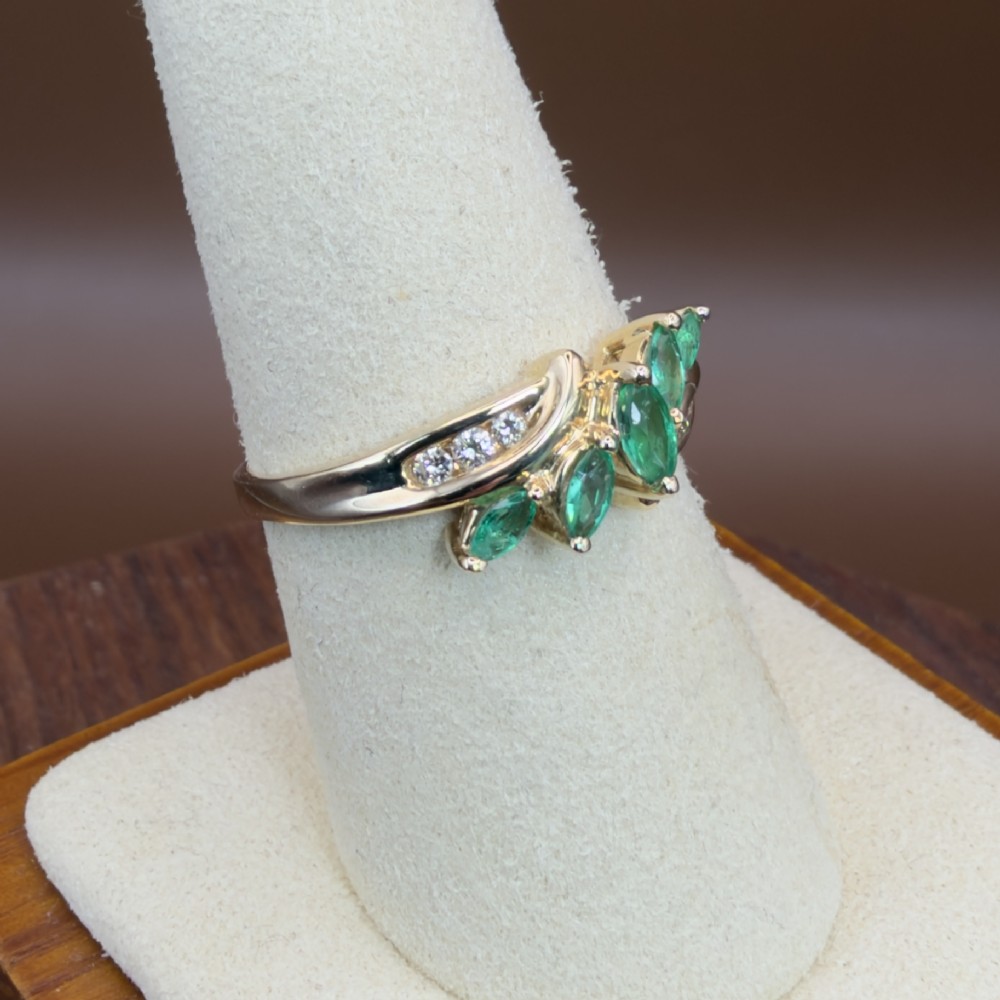 A 14ct yellow gold cluster ring set with five marquise-cut green emeralds flanked by channel-set diamonds. View X