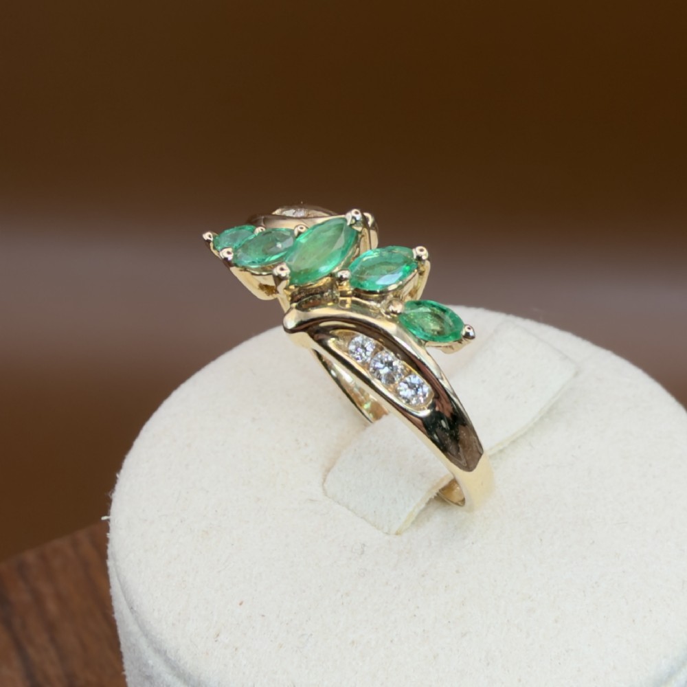 A 14ct yellow gold cluster ring set with five marquise-cut green emeralds flanked by channel-set diamonds. View XI