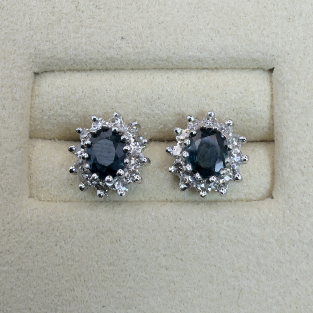 A pair of vintage 9ct gold stud earrings featuring oval deep blue sapphires surrounded by clusters of small diamonds. View II