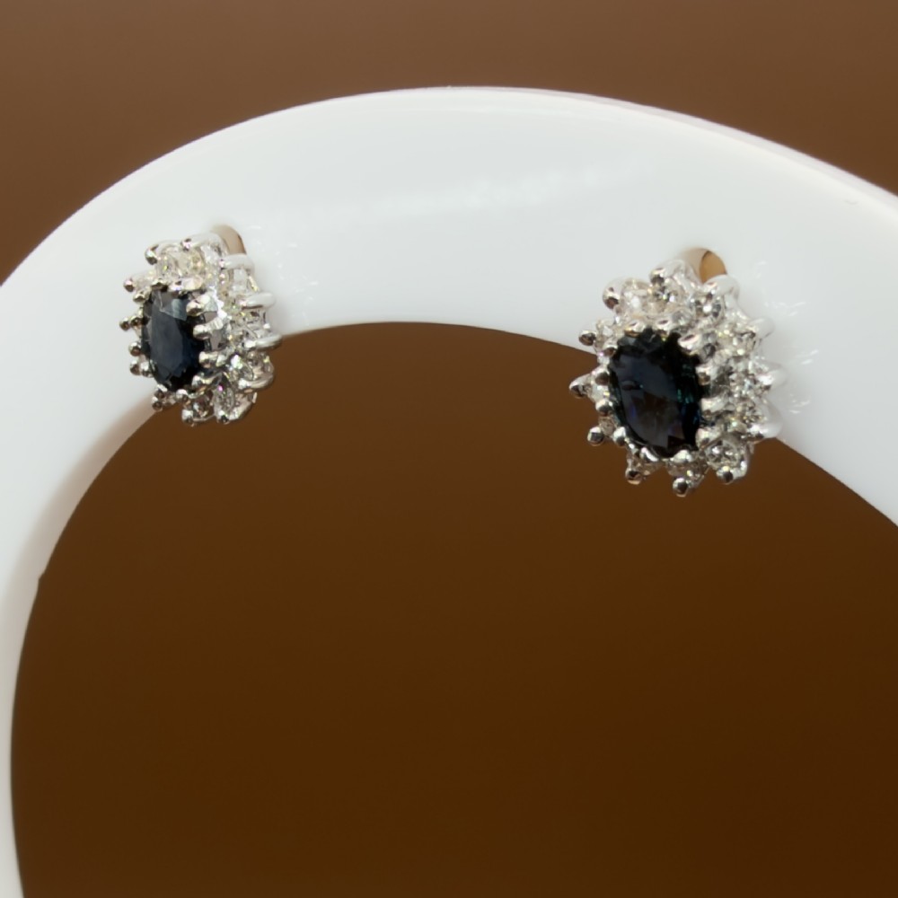 A pair of vintage 9ct gold stud earrings featuring oval deep blue sapphires surrounded by clusters of small diamonds. View VII