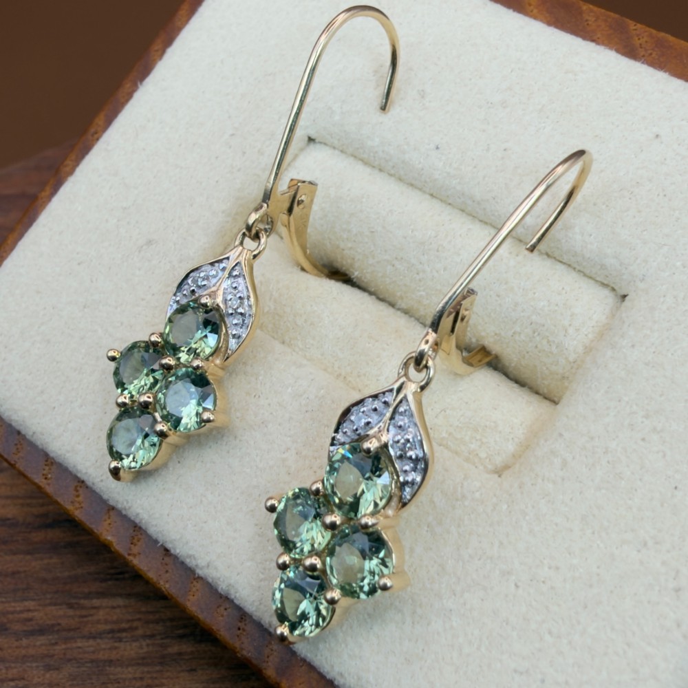 A pair of 9ct yellow gold drop earrings featuring a cluster of round-cut teal green sapphires suspended from hinge back hooks with diamond accent detail. View III