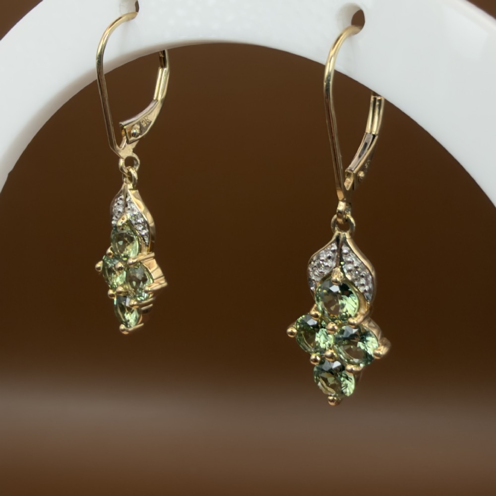 A pair of 9ct yellow gold drop earrings featuring a cluster of round-cut teal green sapphires suspended from hinge back hooks with diamond accent detail. View V