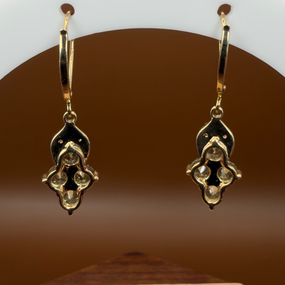 A pair of 9ct yellow gold drop earrings featuring a cluster of round-cut teal green sapphires suspended from hinge back hooks with diamond accent detail. View VII